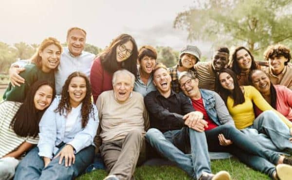 Happy multigenerational people having fun sitting on grass in a public park